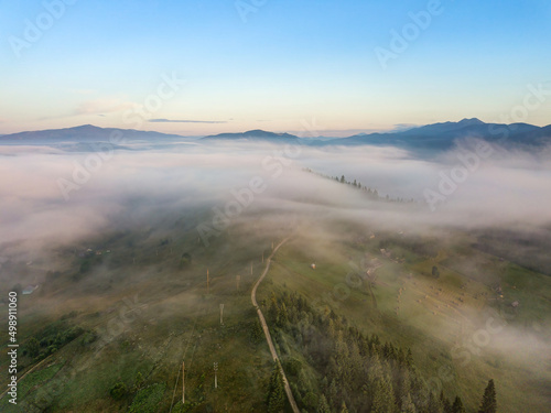 The rays of dawn over the fog in the Ukrainian Carpathians. Aerial drone view.