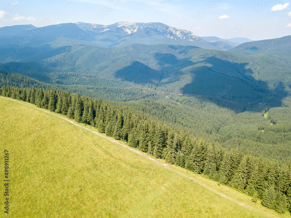 Green mountains of Ukrainian Carpathians in summer. Sunny day, rare clouds. Aerial drone view.