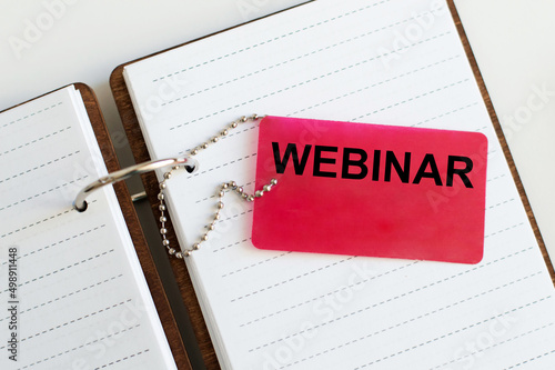 A business card with webinar text on the background of an open notebook on the table, a business concept
