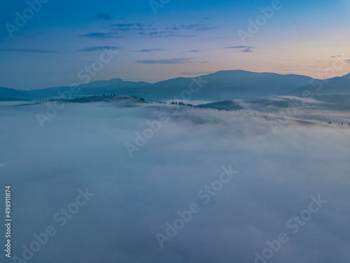 The rays of dawn over the fog in the Ukrainian Carpathians. Aerial drone view.