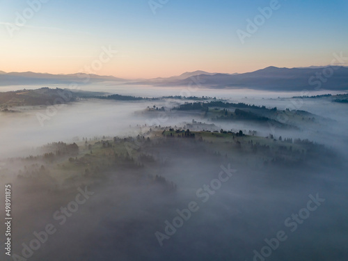 Flight over fog in Ukrainian Carpathians in summer. Mountains on the horizon. Aerial drone view.