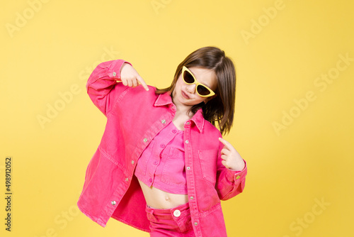 Arrogant little girl pointing herself isolated on yellow background. Egocentric child concept photo