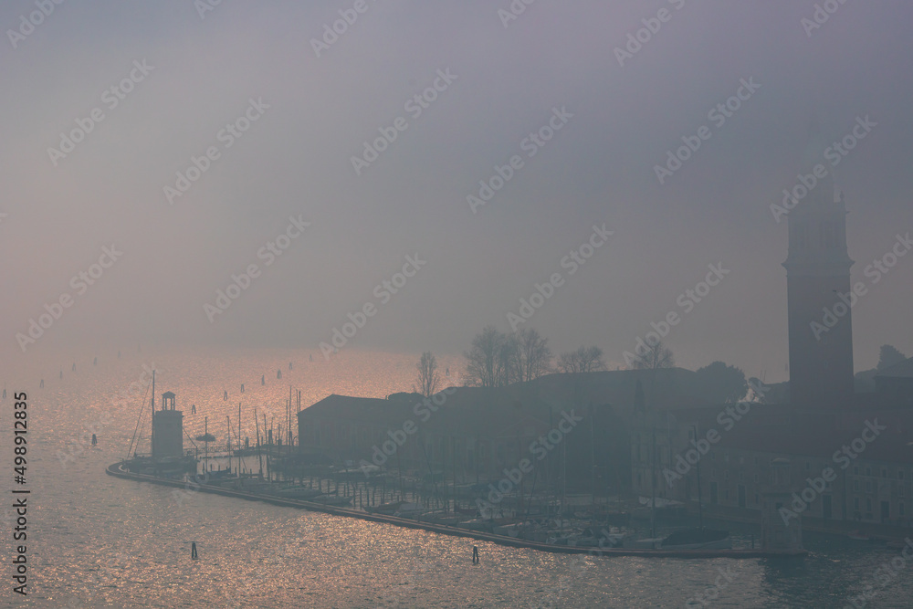 Fototapeta premium Winter foggy urban scene with people walking at coastal street in venice city, Italy