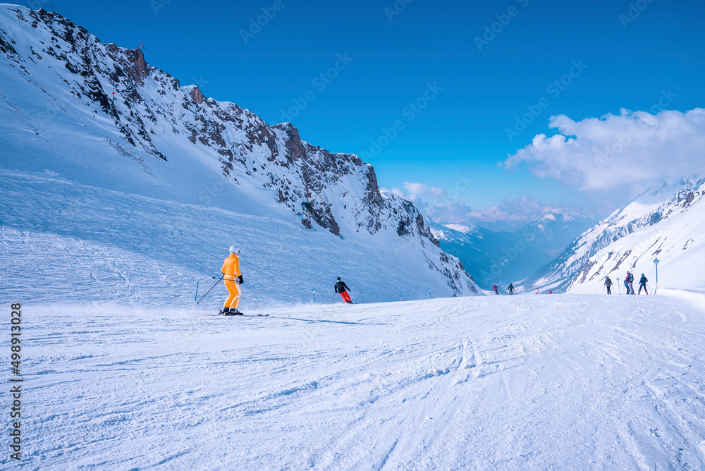 St. Anton am Arlberg. March 10, 2022. People in ski wear sliding down slope on snowy mountain at ski resort during beautiful sunny day, Skiers skiing downhill on snowy mountain