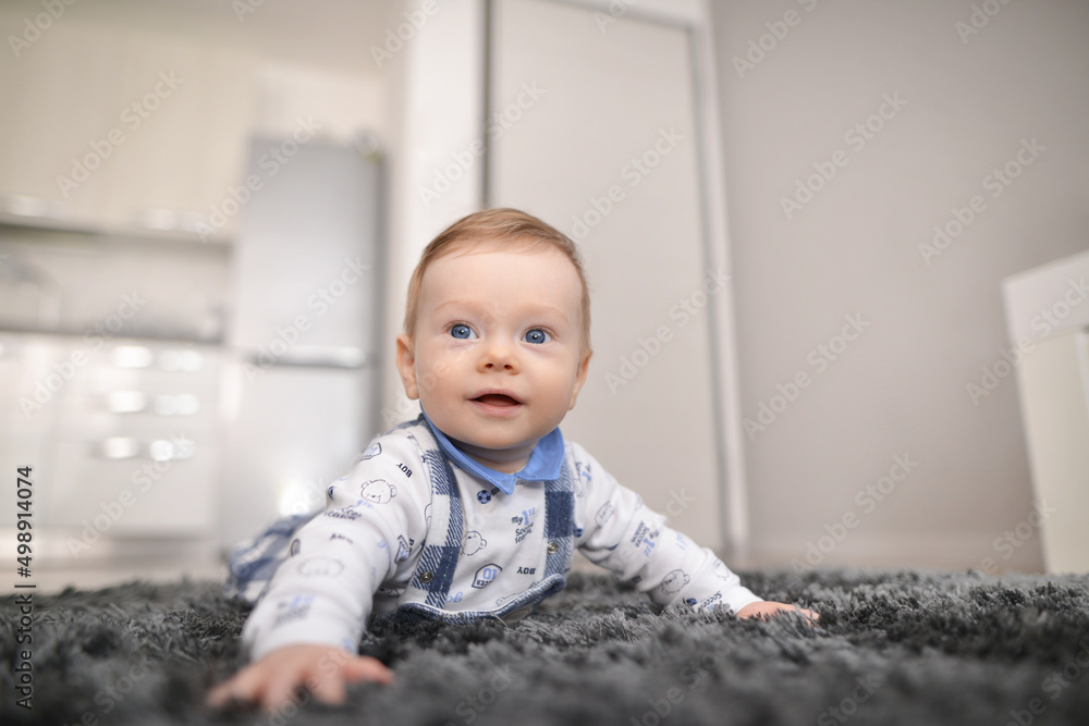 Fototapeta premium Crawling baby on carpet at home. Beautiful baby lies on a fluffy carpet.