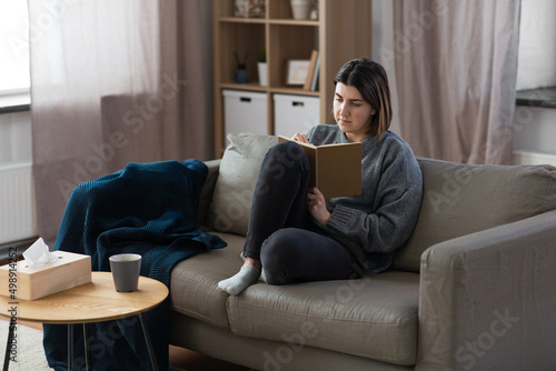 people, leisure and depression concept - sad woman with diary sitting on sofa at home