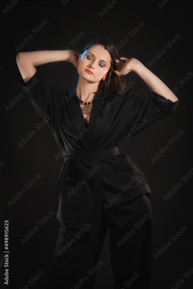 Studio shot in low key with woman with raised hands in black clothes Studio shot in low key with woman with raised hands in black clothes