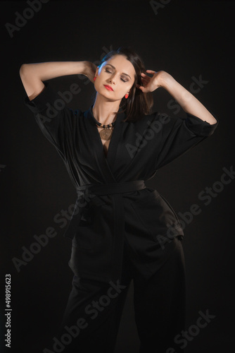 Studio shot in low key with woman with raised hands in black clothes