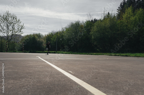 BOY IN BLACK TRACKSUIT HITS THE BALL WITH HIS FOOT ON AN OUTDOOR FUTSAL FIELD