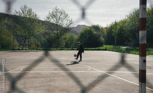 BOY IN BLACK TRACKSUIT FREESTYLE WITH A BALL ON A FUTSAL FIELD