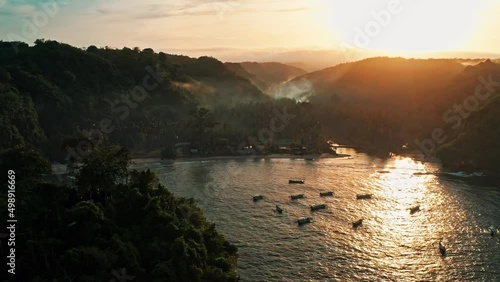 Cinematic nature landscape coastline tropical island in the rays of the rising sun on background mountain landscape and tropical rainforest in fog. 4K Aerial view photo