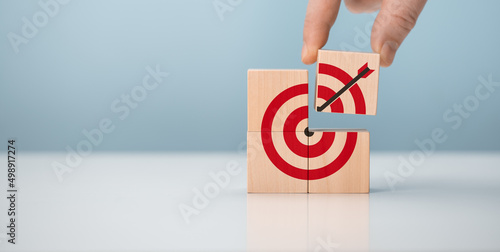 Business achievement goal and objective target concept. Hand man try to complete wooden cube block with DART GOAL TARGET.
