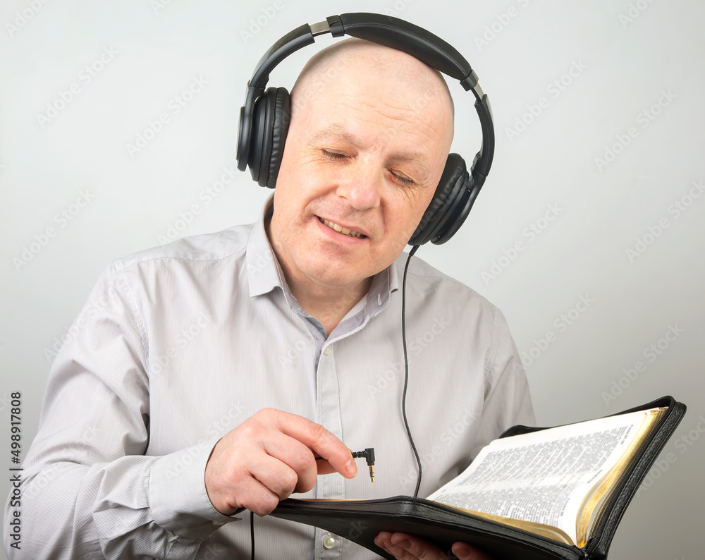 bald man with headphones on his head and an open plug in his hand. Search for a sound source bald man with headphones on his head and an open plug in his hand. Search for a sound source