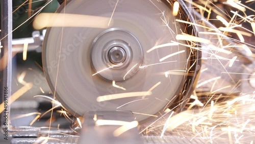 Locksmith in special clothes and goggles works in production. Metal processing with angle grinder. Sparks in metalworking