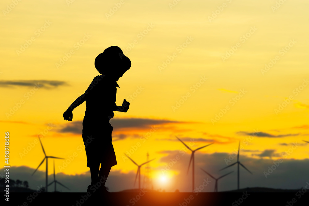 Silhouette of happy kid boy with clipping path playing outdoor at wind farm site on sunset in evening time