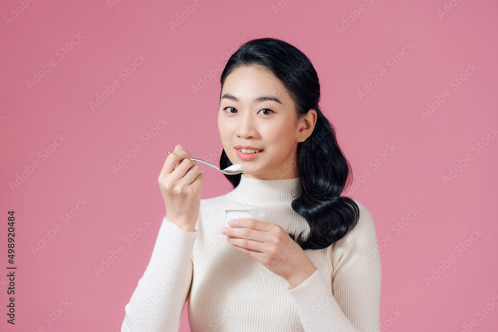 young beautiful smiling woman eating fresh yogurt on pink young beautiful smiling woman eating fresh yogurt on pink