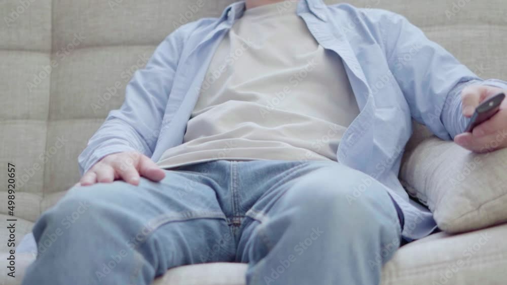 A young man is sitting on the couch watching TV. Leisure time at home A young man is sitting on the couch watching TV. Leisure time at home