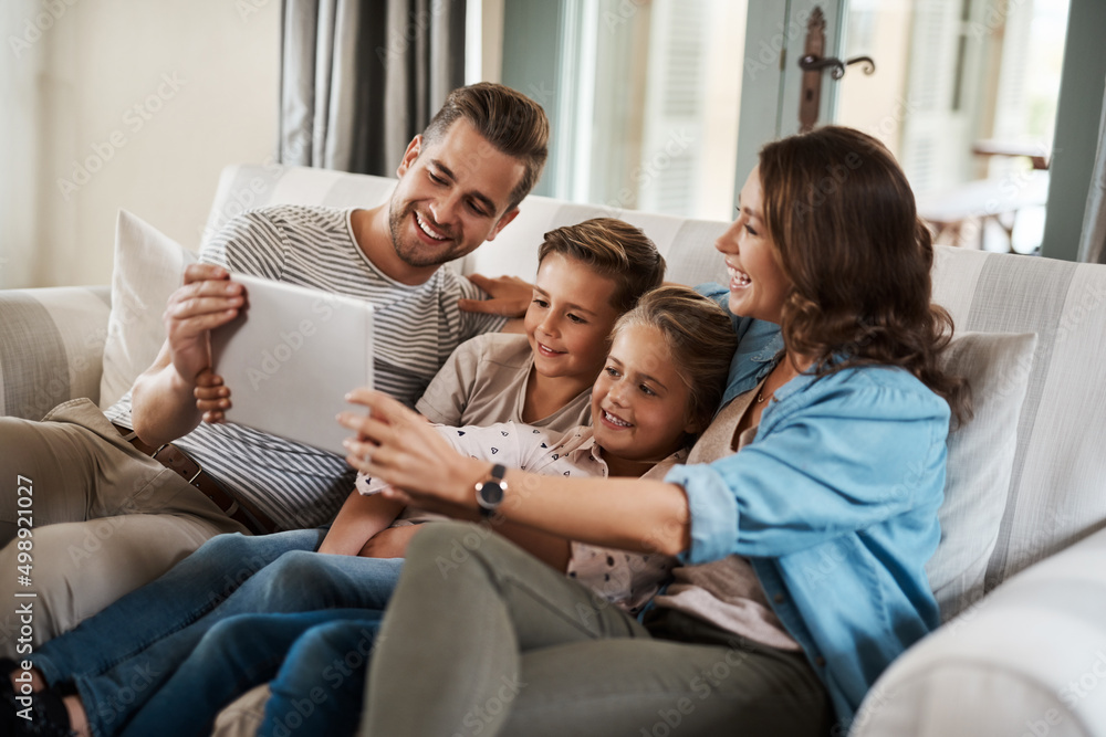 The best way to incorporate learning into playtime. Shot of a happy young family of four using a digital tablet together on the sofa at home.