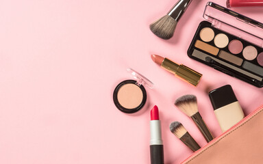 Make up products at pink background with cosmetic bag. Eye shadow, lipstick, powder, brushes and more for professional make up. Flat lay image.