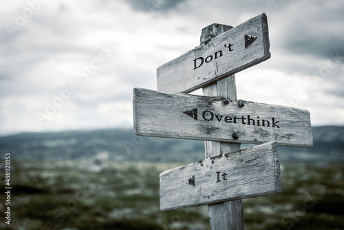 dont overthink it text quote written in wooden signpost outdoors in nature. Moody theme feeling. photo