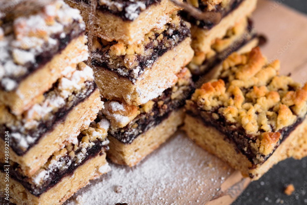 square shortbread cookies with jam close-up. Coffee beans sprinkled with powdered sugar are scattered on the table. On a gray background. square shortbread cookies with jam close-up. Coffee beans sprinkled with powdered sugar are scattered on the table. On a gray background.