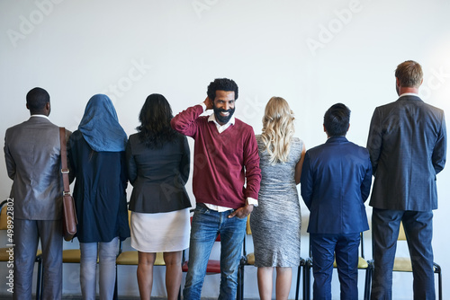 It pays to have a different perspective. Portrait of a happy job applicant standing in line with a group of unidentifiable businesspeople.