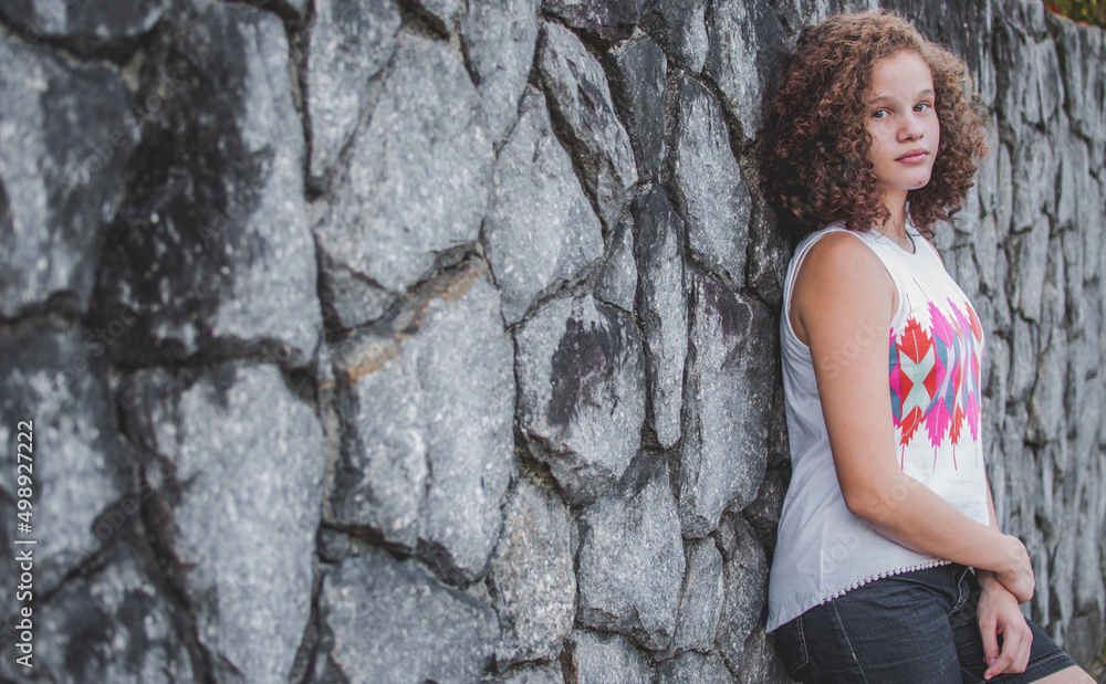 Portrait of girl leaning against stone wall - Curly hair - Copy space Portrait of girl leaning against stone wall - Curly hair - Copy space