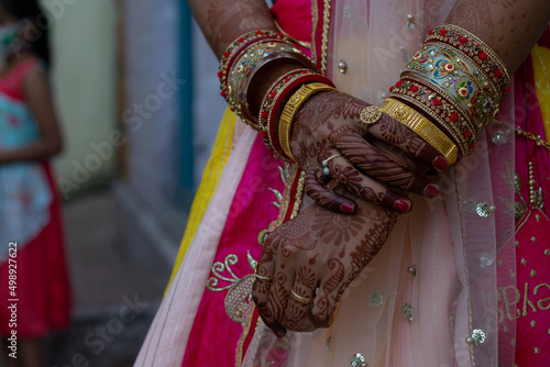 Picture of tattooed(mehndi, henna) hand of an Indian woman or bride along with jewelry such as bangles, rings during festival and marriage, forced, arranged, inter caste, love, dowry, violence, groom.