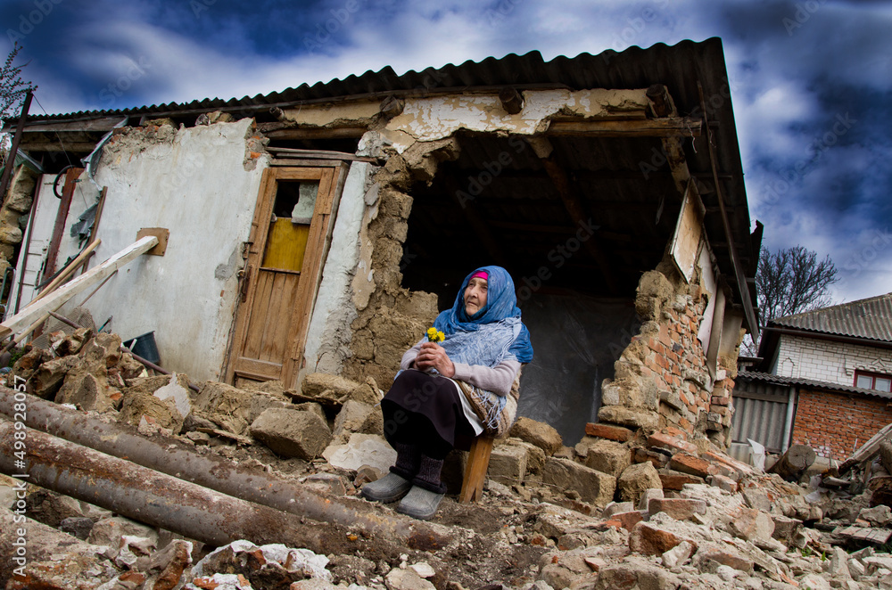 A woman in front of a war-torn house. War in Ukraine. Ukrainian refugees. Grandmother prays for peace in Ukraine. A destroyed house after a bombing in Ukraine. Russian aggression against Ukraine A woman in front of a war-torn house. War in Ukraine. Ukrainian refugees. Grandmother prays for peace in Ukraine. A destroyed house after a bombing in Ukraine. Russian aggression against Ukraine