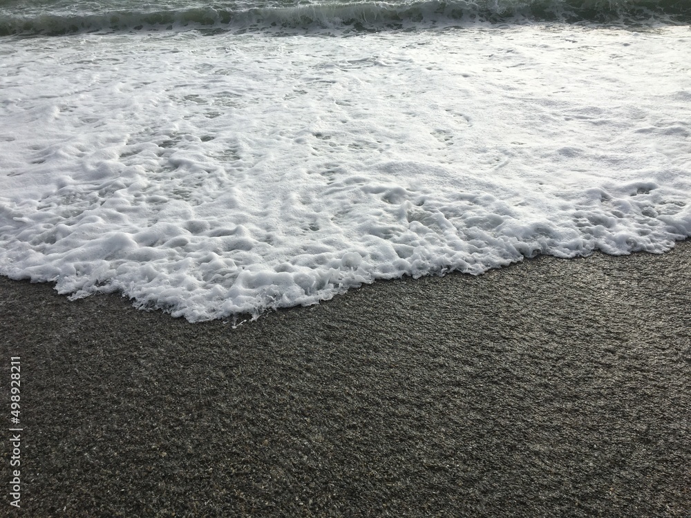 Obraz premium Black Sea coast, sunny day with a view of the blue sky horizon and sea foam waves. Pebbles - round sea stones. Sea stones, pebbles, sea foam, pebbles on the seashore
