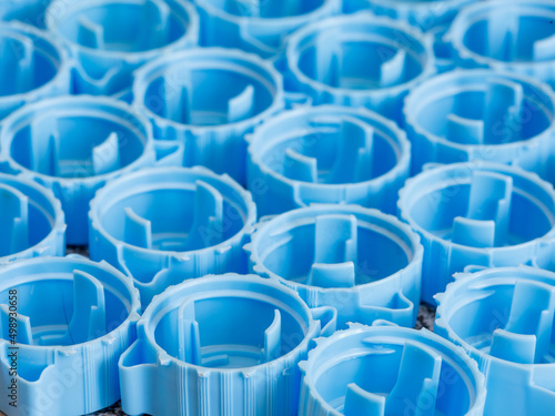 Small blue plastic bottle caps background. Recycling collection and production processing plastic bottle caps. Side view, close up