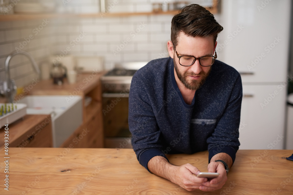 Making plans for his day of leave. Cropped shot of a handsome young man sending a text message while standing in the kitchen at home. Making plans for his day of leave. Cropped shot of a handsome young man sending a text message while standing in the kitchen at home.