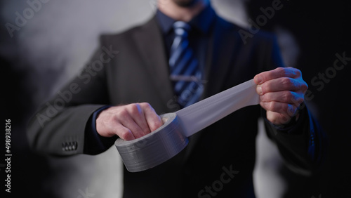 Headless businessman on black background with smoke roll out silver tape