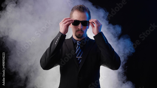 Male businessman on black background put on sunglasses with blasting smoke like a boss