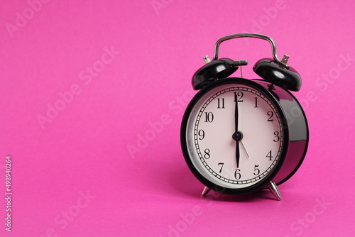 vintage old black alarm clock on pink background