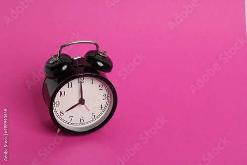 vintage old black alarm clock on pink background 