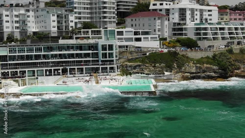 Bondi Icebergs Swimming Club on day with rough sea, Bondi Beach in Australia. Aerial circling photo