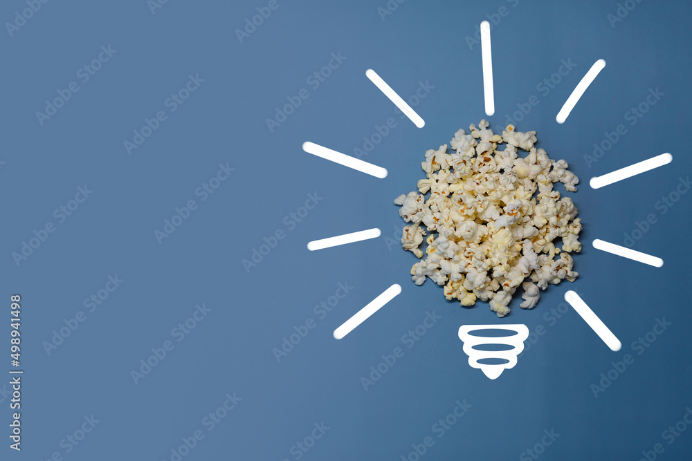 Idea symbol in the form of light bulb from popcorn on blue background. Time for cinema. Idea symbol in the form of light bulb from popcorn on blue background. Time for cinema.