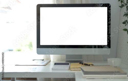 Blank screen desktop computer in minimal office room with decorations and copy space