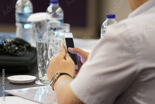 Foto man hand holding white mobile with black screen in meeting room