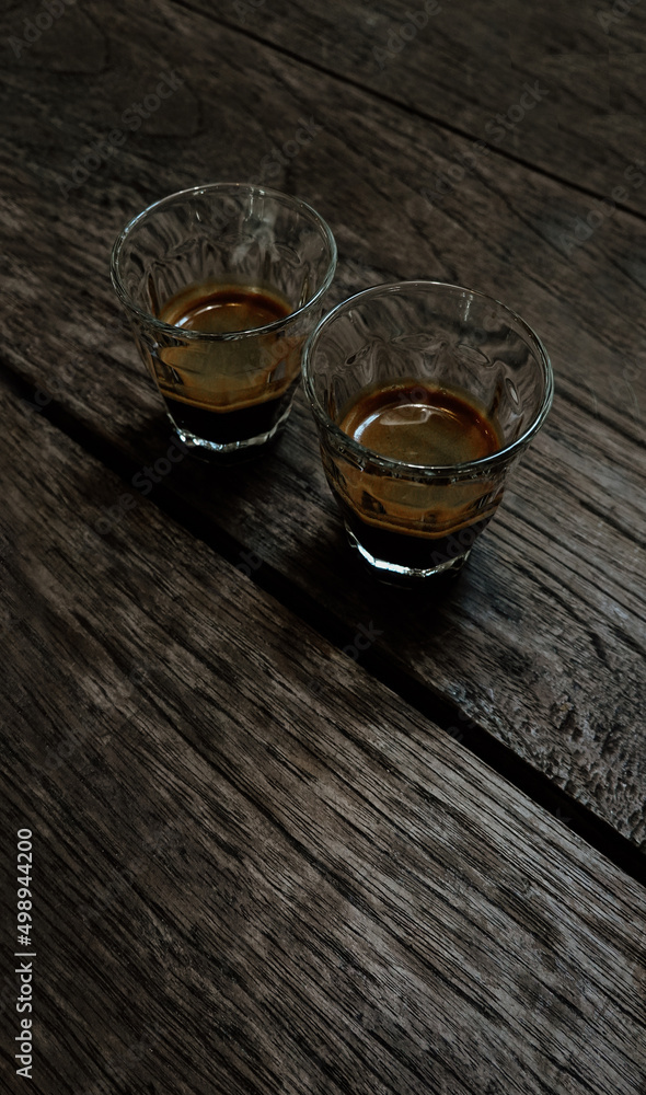 A cup of espresso shot coffee in a glass cup on wooden table background A cup of espresso shot coffee in a glass cup on wooden table background