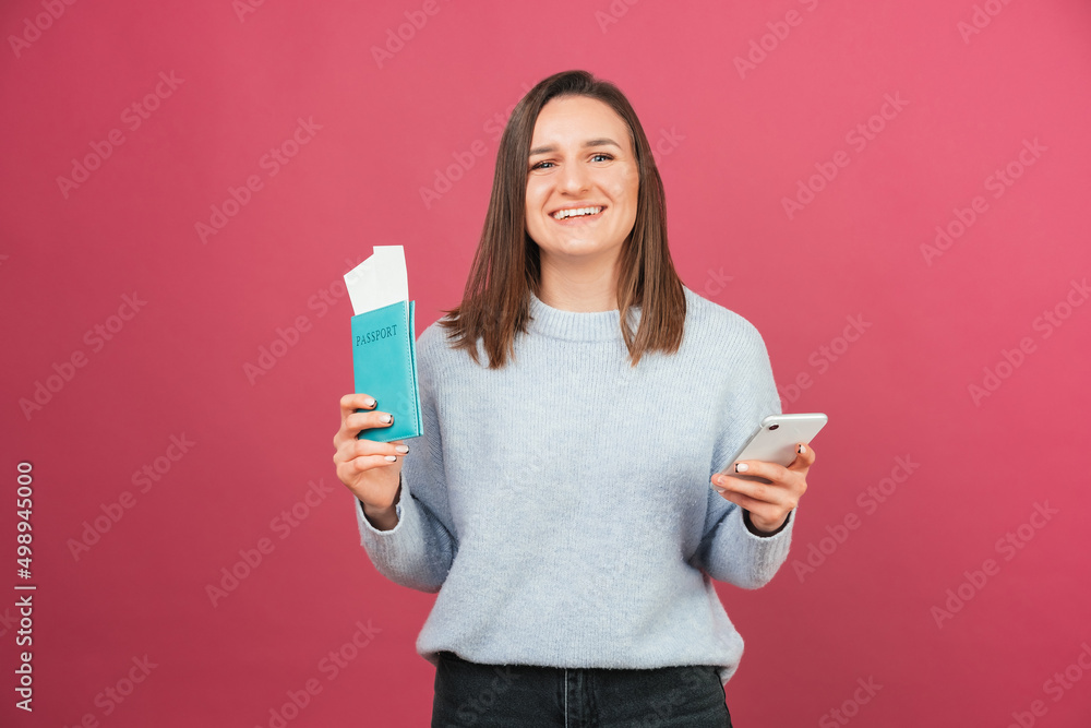 Excited woman has just checked in online on the phone while holding passport. Studio shot over pink wall. Excited woman has just checked in online on the phone while holding passport. Studio shot over pink wall.