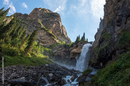 Beautiful waterfall in mountains with. Barskoon waterfall - splashes of Champaign. Travel, tourism in Kyrgyzstan concept.