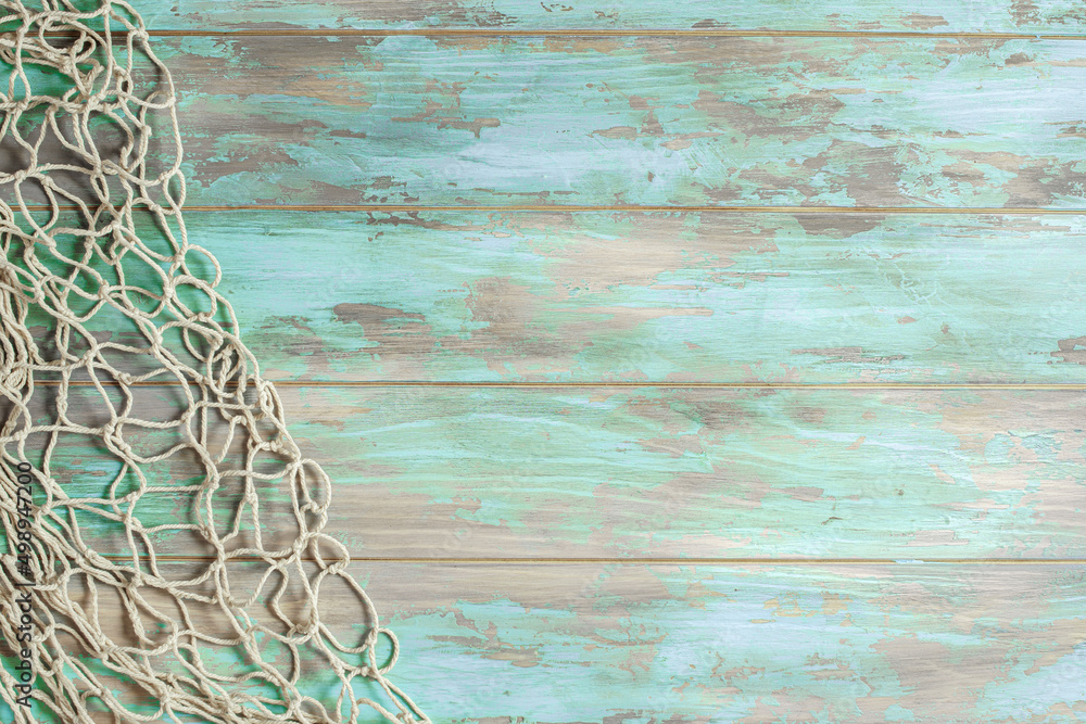 Fishing net on old cyan board background with copy space - obrazy, fototapety, plakaty 