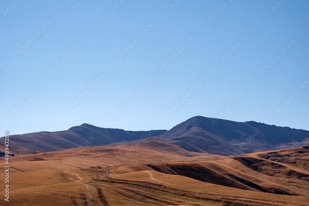 Beautiful mountains with dried orange grass and road going up in autumn season. Natural background. Assy plateau in Ili-Alatau national park.
