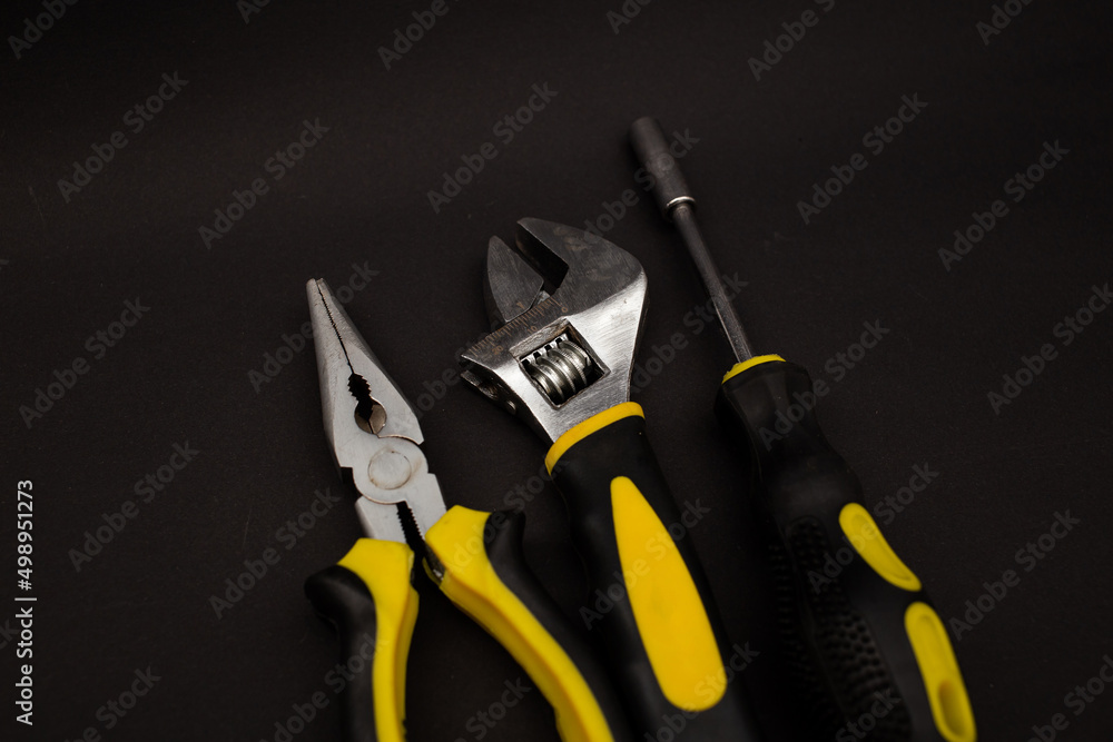 Screwdriver, pliers and plumber's wrench, detailed shot in the background Screwdriver, pliers and plumber's wrench, detailed shot in the background