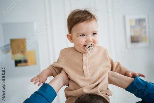 joyful child with a pacifier in his father's arms