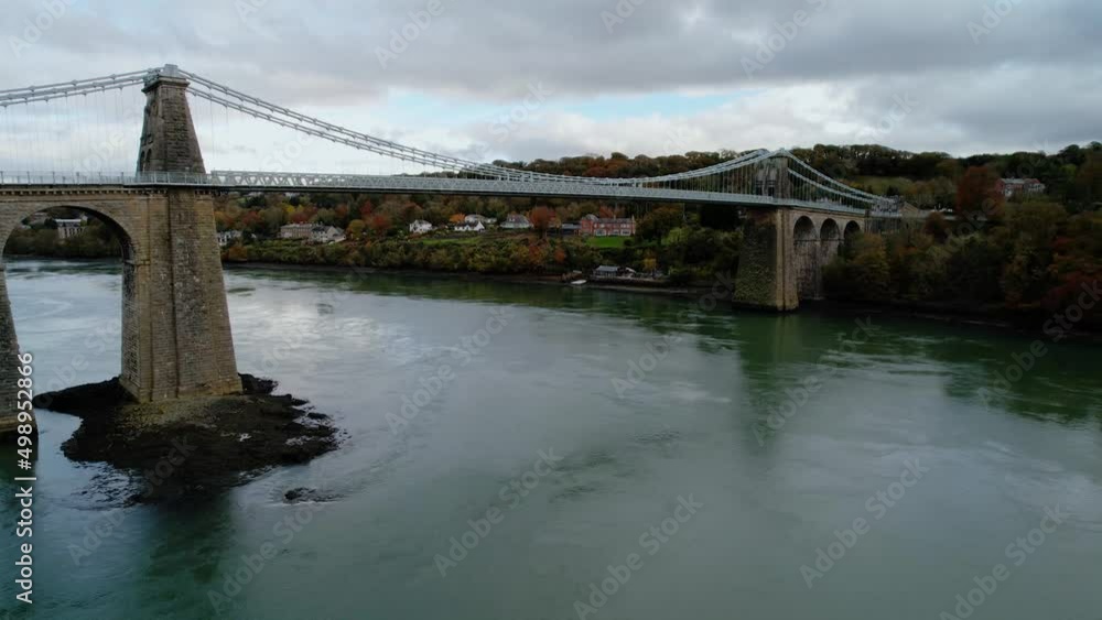 Menai Suspension Bridge, Anglesey in North Wales. Aerial tilt down ascendent Menai Suspension Bridge, Anglesey in North Wales. Aerial tilt down ascendent