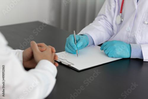 The doctor is writing the patient's history while asking about his illness and giving health advice. Professional doctor or pharmacist works in the office and writes prescriptions.