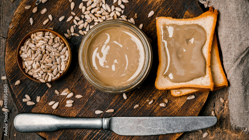 Fotografia Sunflower paste in a small bowl, a jar and a piece of bread